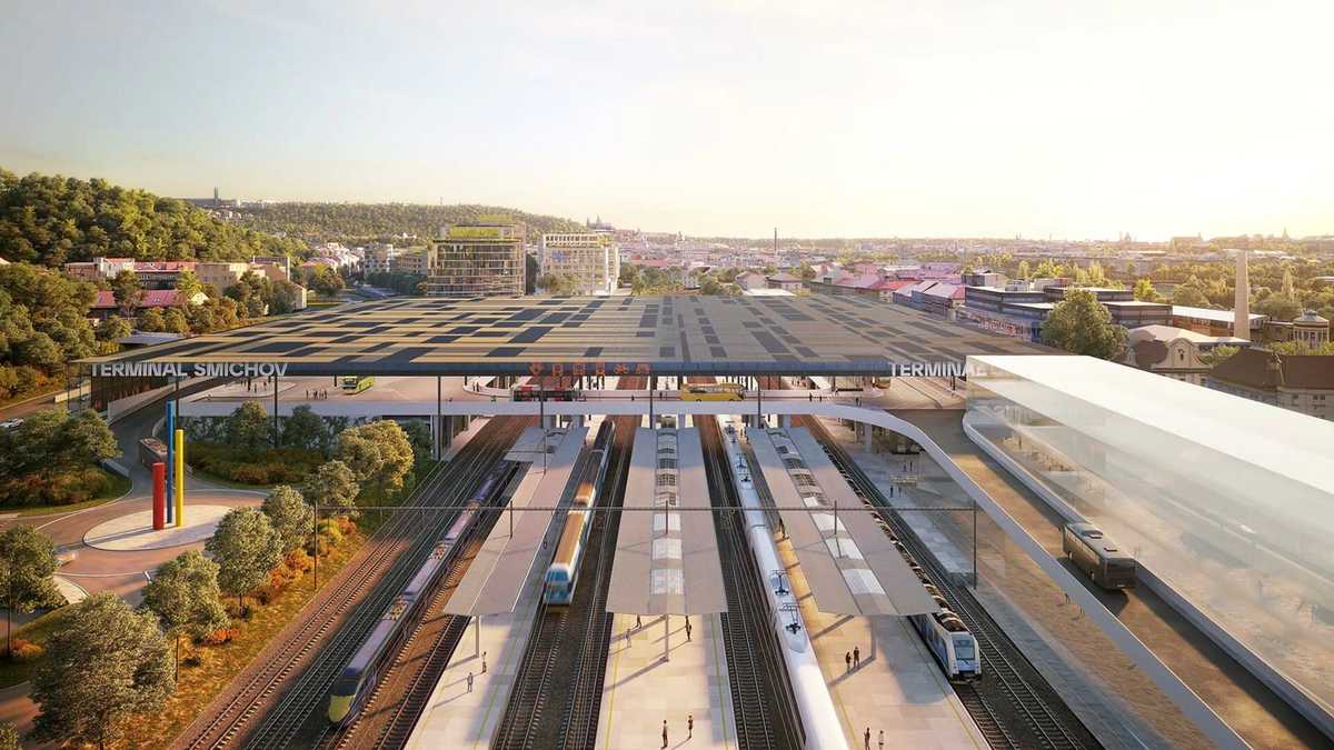Vizualizace Terminálu Smíchov při pohledu shora nad kolejiště: dlouhá tmavá střecha nad nástupišti s nápisem TERMINAL SMICHOV, přes nádraží vede lávka k prosklené hale vpravo, u nástupišť stojí vlaky a za nimi stoupá město k Petřínu.